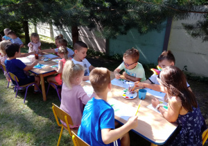 Dzieci malują farbami w ogrodzie przedszkolnym